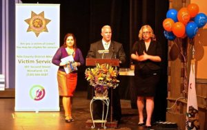 Photo from the 2016 Victim Tribute Ceremony, from left to right, Victim Advocate Program Coordinator Laura Valdes, District Attorney Jeff Reisig, & the Sign-Language Translator.