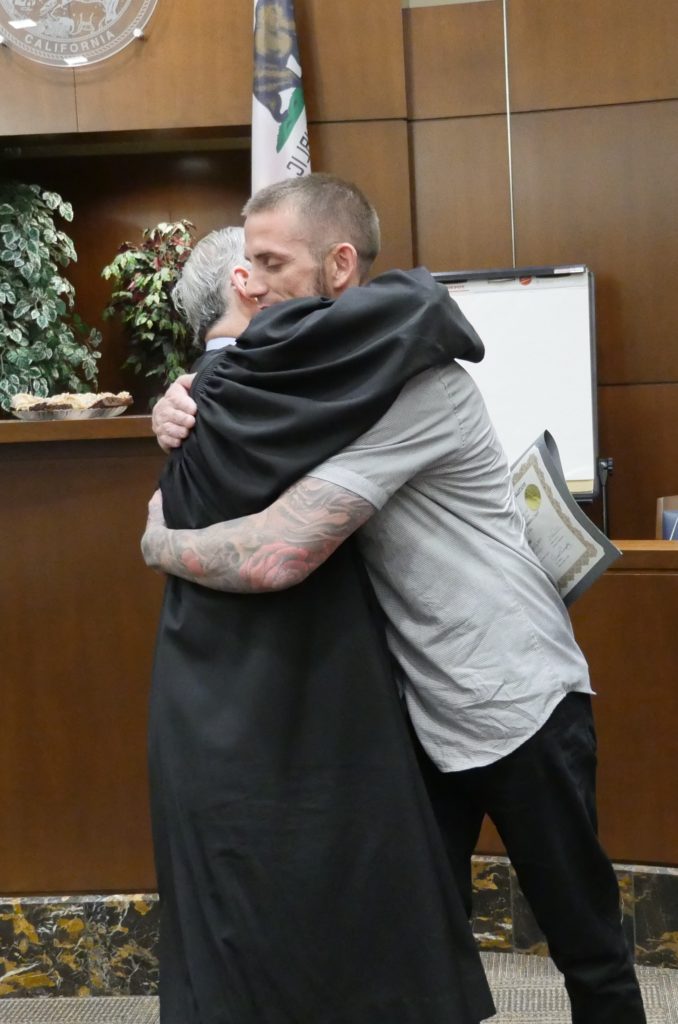 Image depicts AIC graduate giving the judge a hug