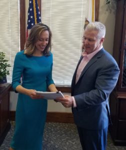 Image depicts Yolo County DA Jeff Reisig presenting the restitution check to First 5 Yolo Executive Director, Gina Daleiden.