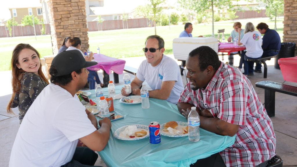 Image depicts Chief DDA Jonathan Raven chatting with MHC graduates over lunch.