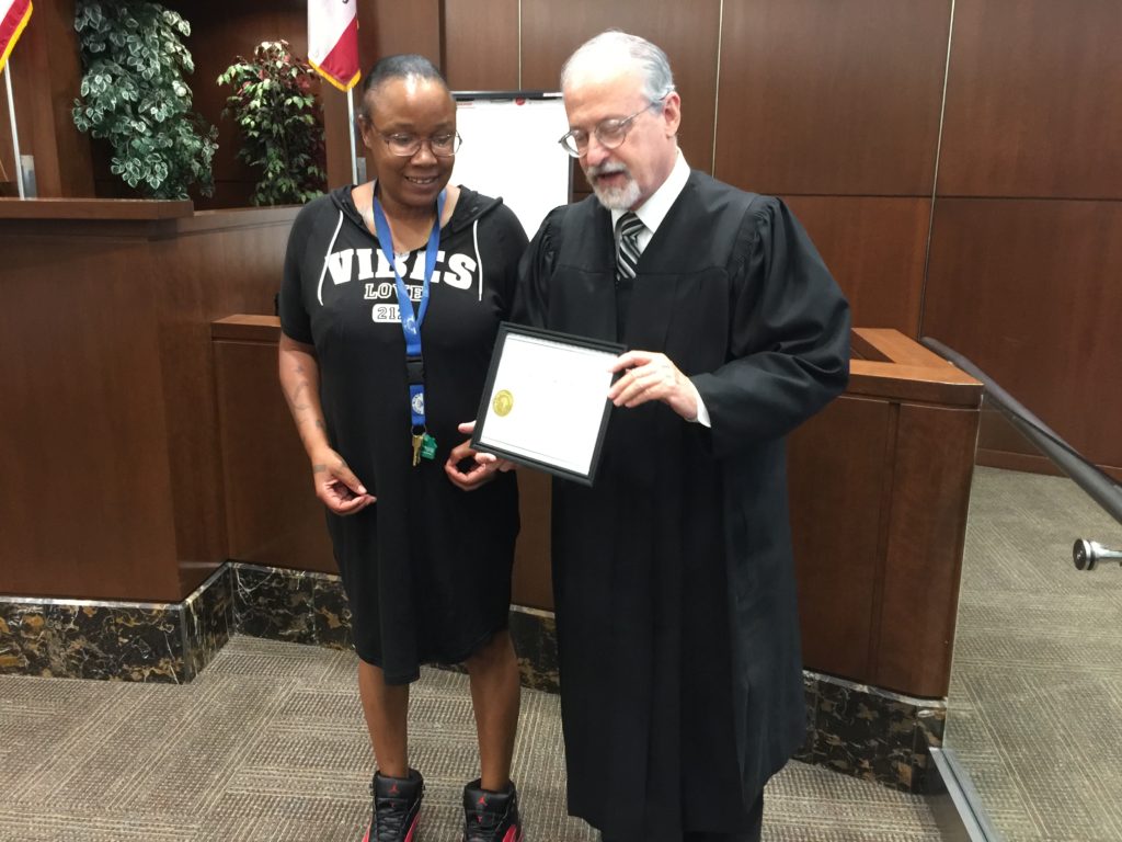 Image depicts Judge Rosenberg presenting MHC participant Subrina Seaton with her certificate of completion.