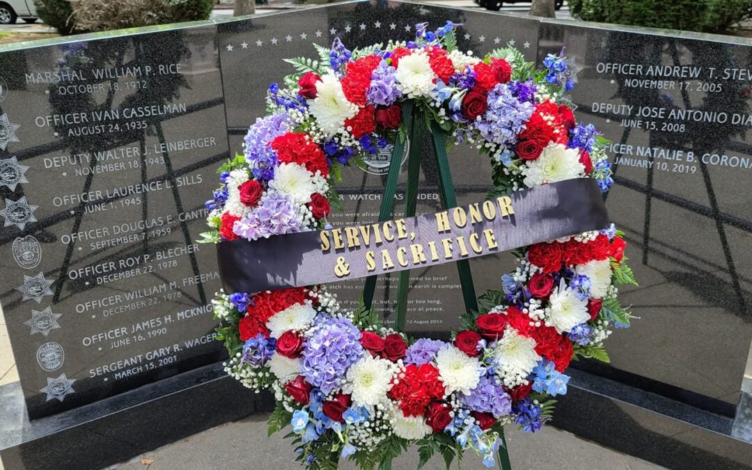 Image depicts the fallen peace officer memorial with a wreat made of red, white and blue flowers.