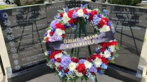 Image depicts the fallen peace officer memorial with a wreat made of red, white and blue flowers.