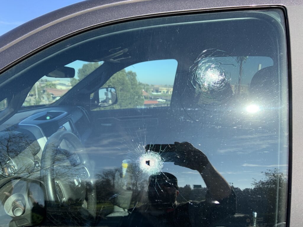 Image depicts one of the victims' vehicles with bullet holes in the window.